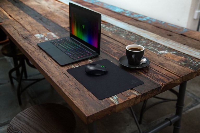 Razer Goliathus Mobile Stealth Edition Mat with Razer Blade Stealth Laptop and Razer Orochi Mouse - Public Cafe Table (Angled View)